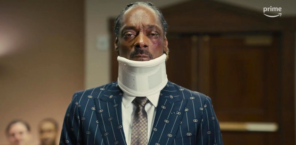 Snoop Dogg acting in an Amazon Prime project, with a bruise on his face and wearing a neck brace 