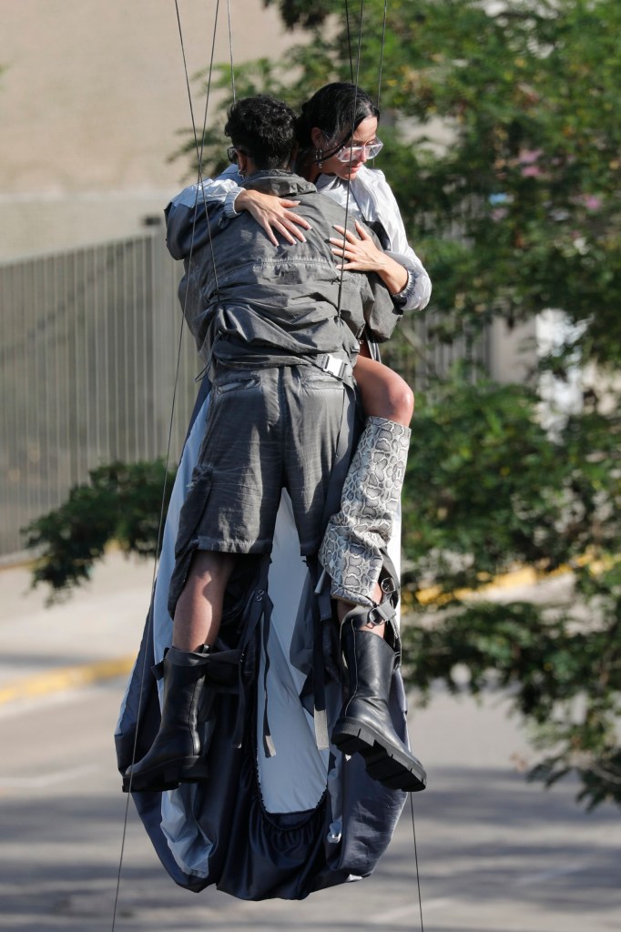 Katy Perry clutching onto a stuntman on the set of her new music video