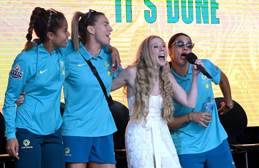 Mary Fowler, Steph Catley and Sam Kerr sing along with Nikki Webster