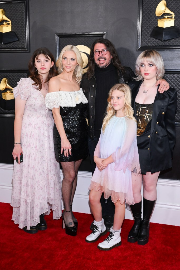 Dave Grohl and his wife Jordyn Blum and their three daughters posing on a red carpet