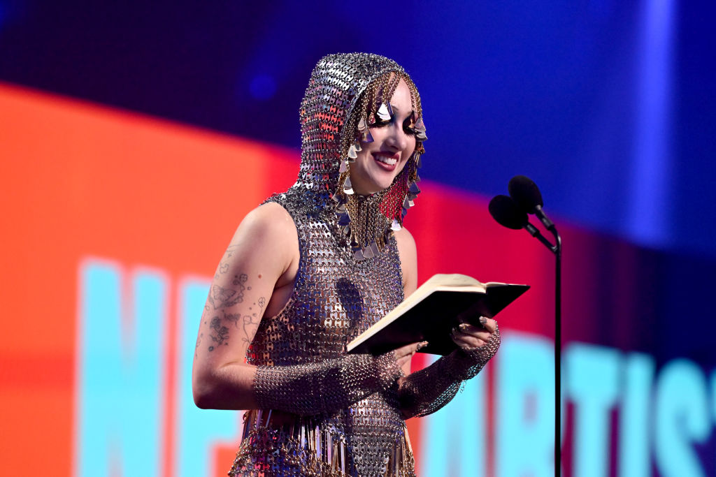 Chappell Roan giving her VMAs acceptance speech from her diary. She is wearing a chainmail bodysuit with a hood