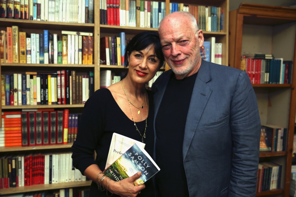 Polly Sampson and David Gilmour pose for a photo in front of a bookshelf