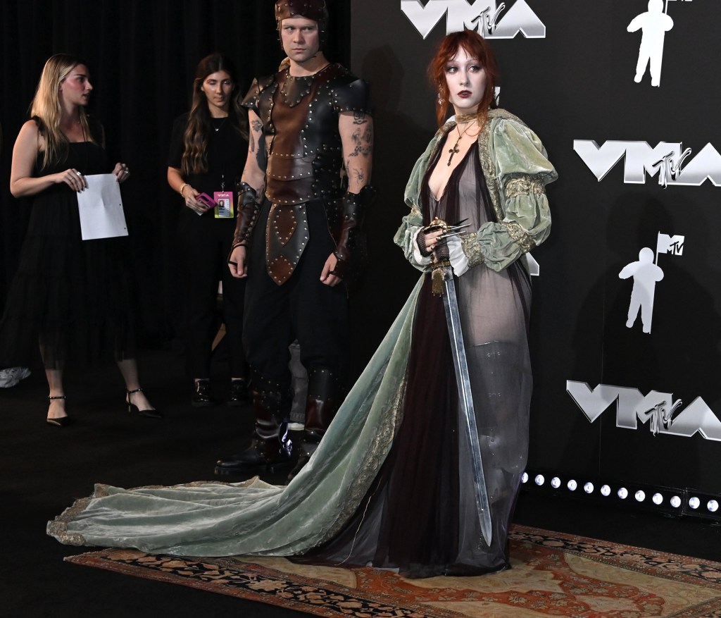 Chappell Roan on the red carpet for the 2024 MTV Video Music Awards holding a sword and standing next to a man dressed as a knight