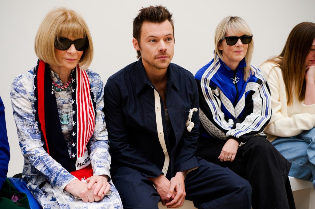 Anna Wintour and Harry Styles sitting in the front row at London Fashion Week, with Harry wearing a navy outfit and sporting a new shorter haircut