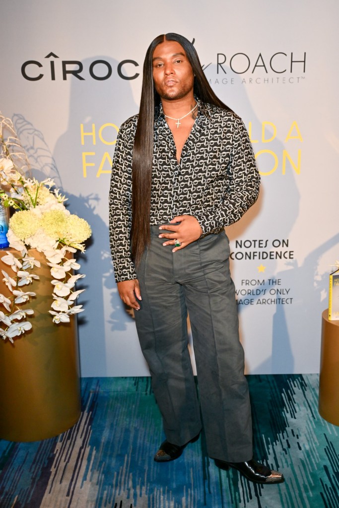 Law Roach posing in front of a Ciroc backdrop in a black and white shirt