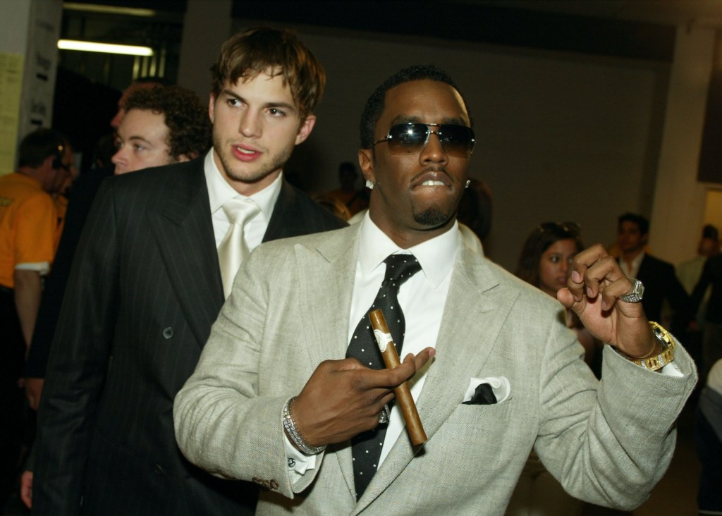 Sean 'Diddy' Combs and Ashton Kutcher at the MTV Movie Awards in 2003, both wearing suits and with Diddy holding a cigar