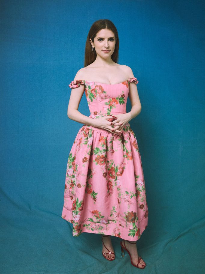 Anna Kendrick in pink floral dress on teal backdrop 