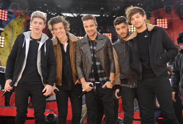 All of the members of One Direction posing on a red carpet and smiling