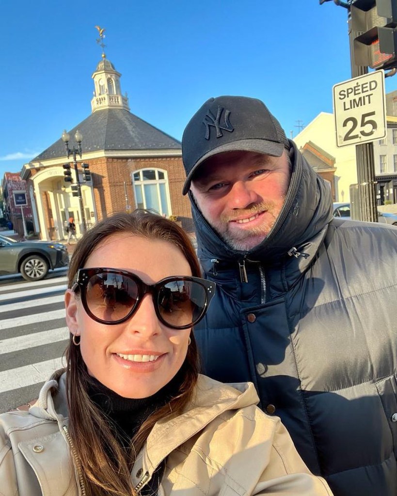 Coleen Rooney wearing sunglasses and Wayne Ronney wearing a hat in a selfie taken by the side of the road