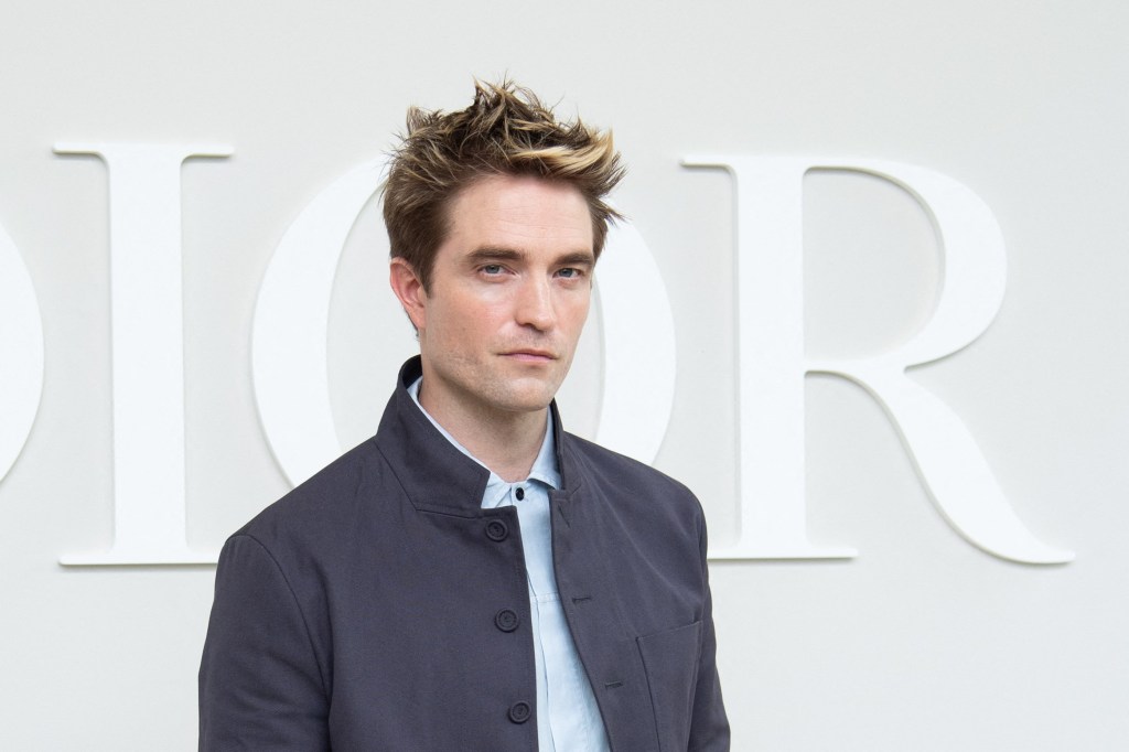  Robert Pattinson posing for a photo on a red carpet