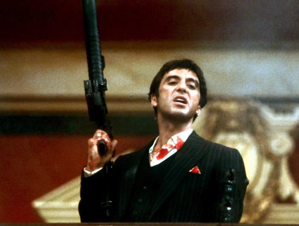  Al Pacino in Scarface holding a gun while covered in blood