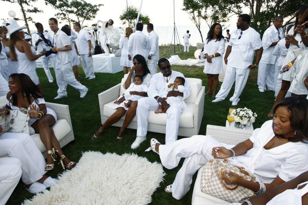 Diddy sits on couch and is surrounded by people wearing white